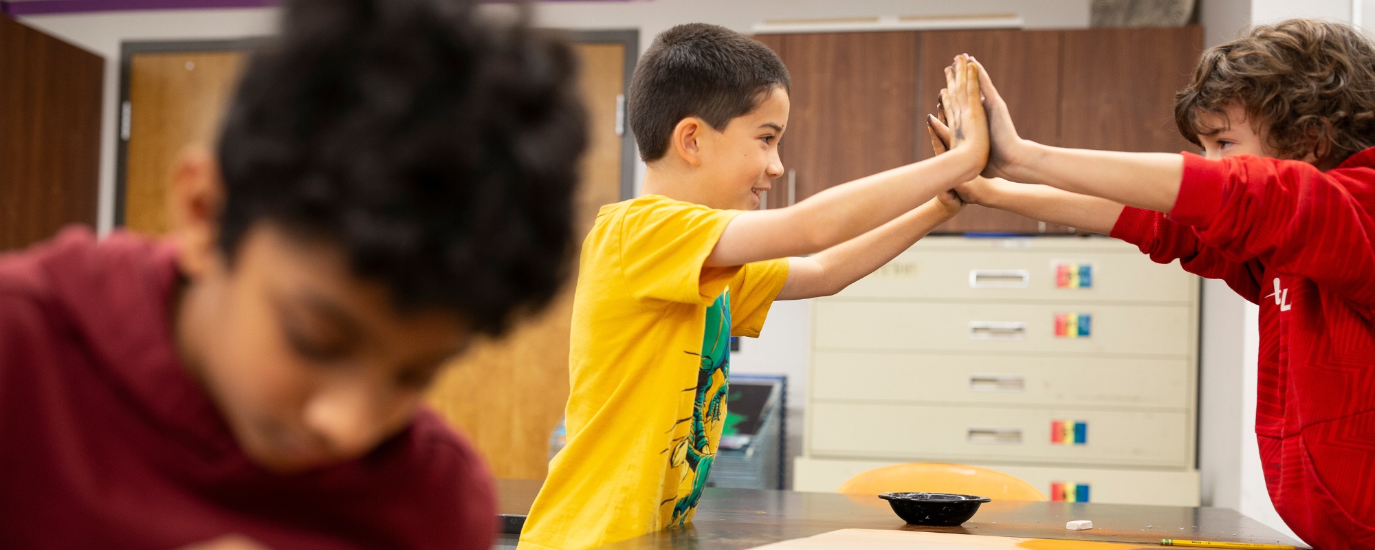 Two kids high five during art class.